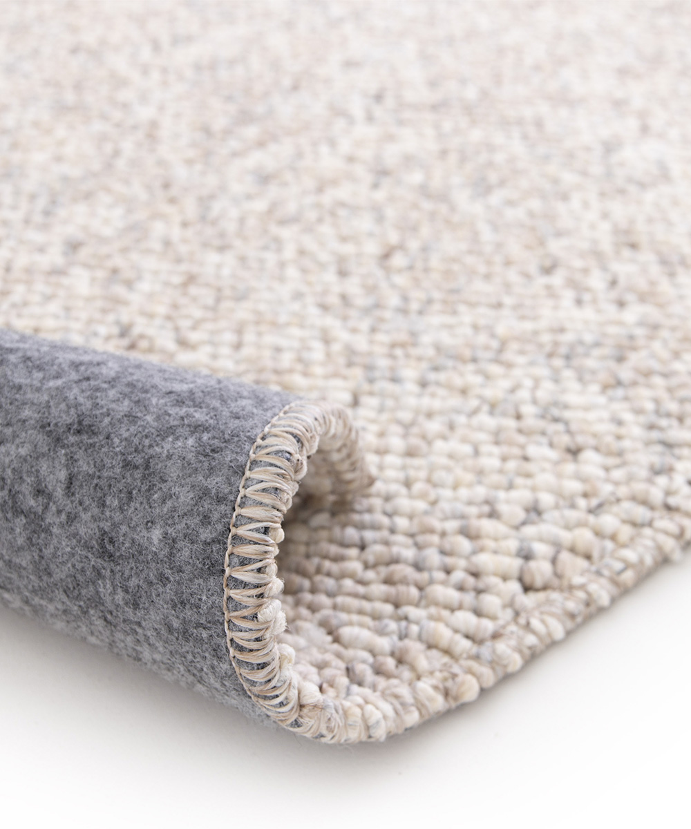 Angolo con spessore del Tappeto bouclé PABLO GREIGE tessitura effetto riccio, colori naturali e design minimal in stile scandinavo. Morbidi, resistenti ma anche pratici e facili da lavare: lavatrice e asciugatrice.